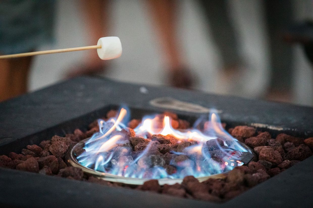 Marshmallow roasting over a blue gas fire in a black fire pit