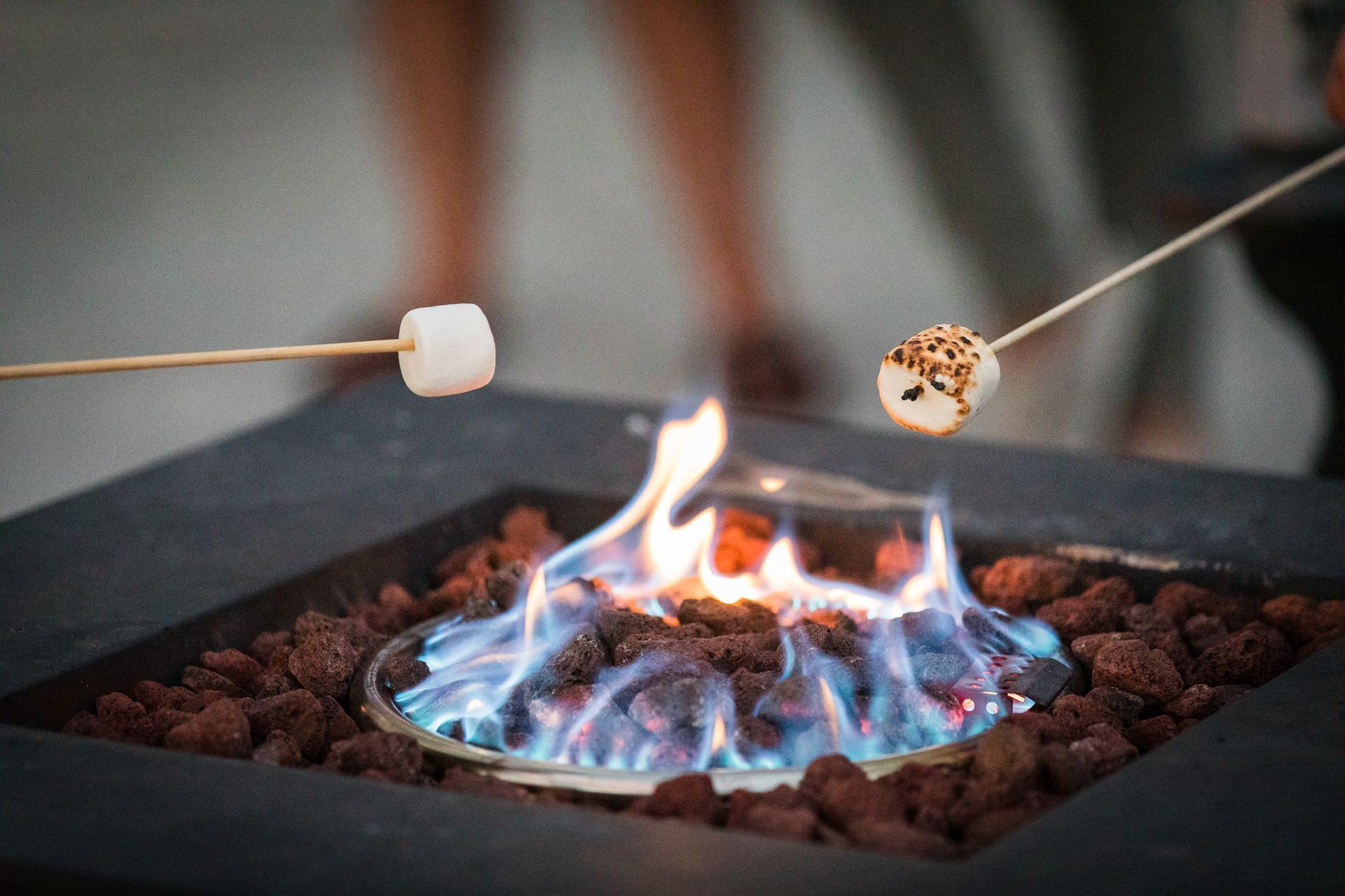 Marshmallows roasting over a blue gas fire pit with lava rocks