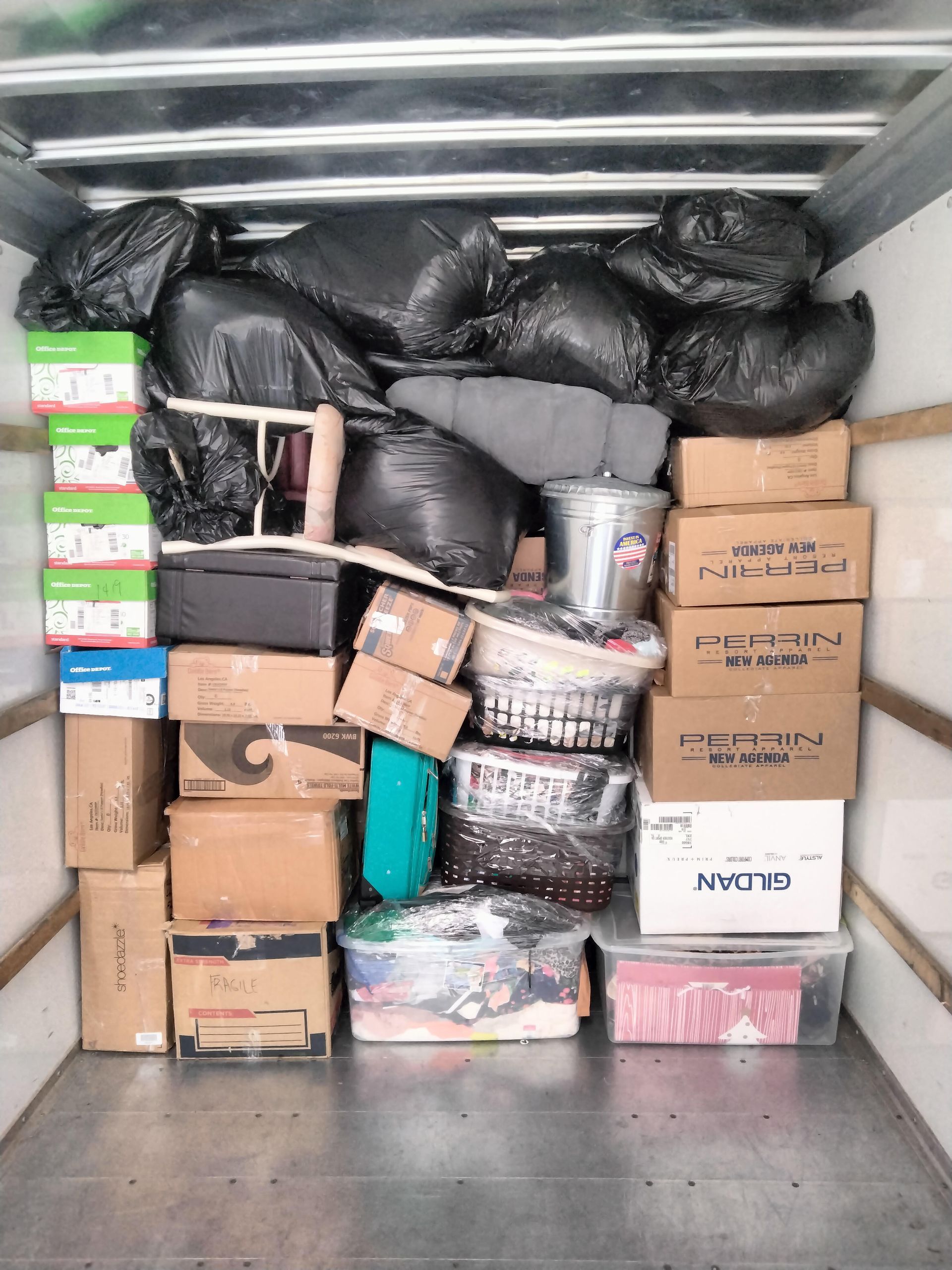 Open van loaded with stacked cardboard boxes at a delivery site