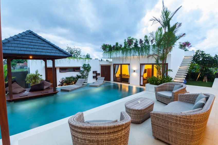 a large swimming pool surrounded by wicker furniture and a gazebo .