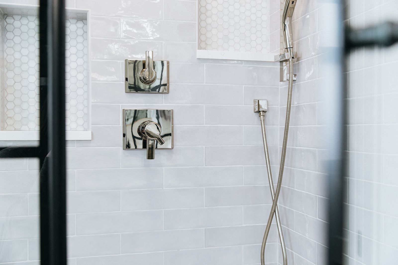 A close up of a shower head in a bathroom with white tiles