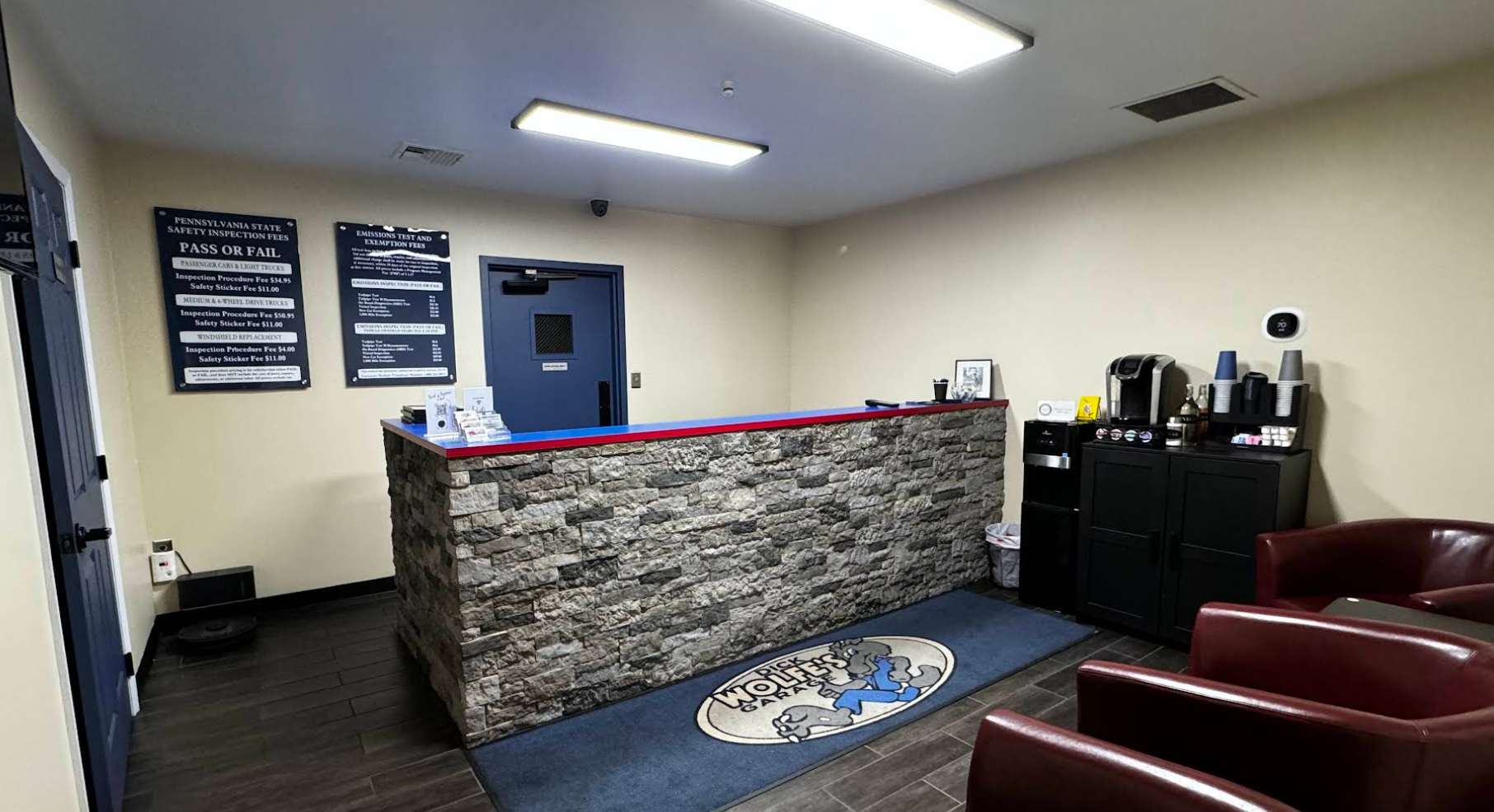 Small office lobby with stone-front reception desk, red chairs, blue rug, and wall signs | Dick Wolfe's Garage