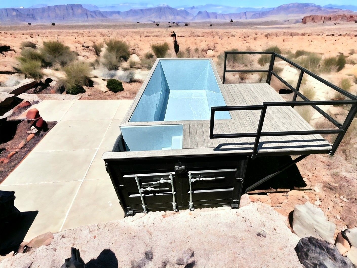 A swimming pool in the middle of a desert with mountains in the background