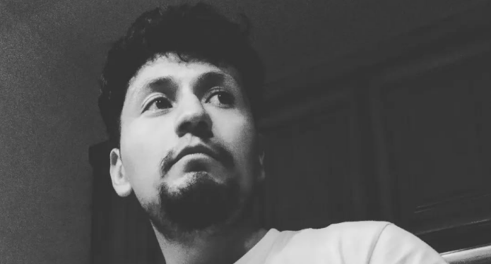 Fotografía en blanco y negro de un hombre mirando hacia arriba con expresión contemplativa.