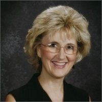 A woman wearing glasses and a black shirt smiles for the camera