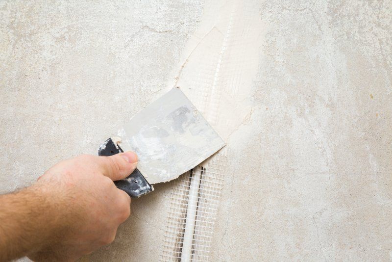 A Person is Plastering a Wall With a Spatula — Clean Line Plastering in Diamond Beach, NSW