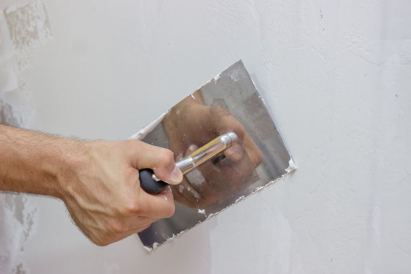 A Person is Plastering a Wall With a Trowel — Clean Line Plastering in Taree, NSW