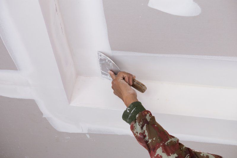 A Person is Plastering a Ceiling With a Spatula — Clean Line Plastering in Forster, NSW