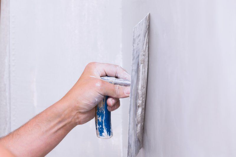 A Man is Plastering a Wall With a Trowel — Clean Line Plastering in Forster - Tuncurry, NSW