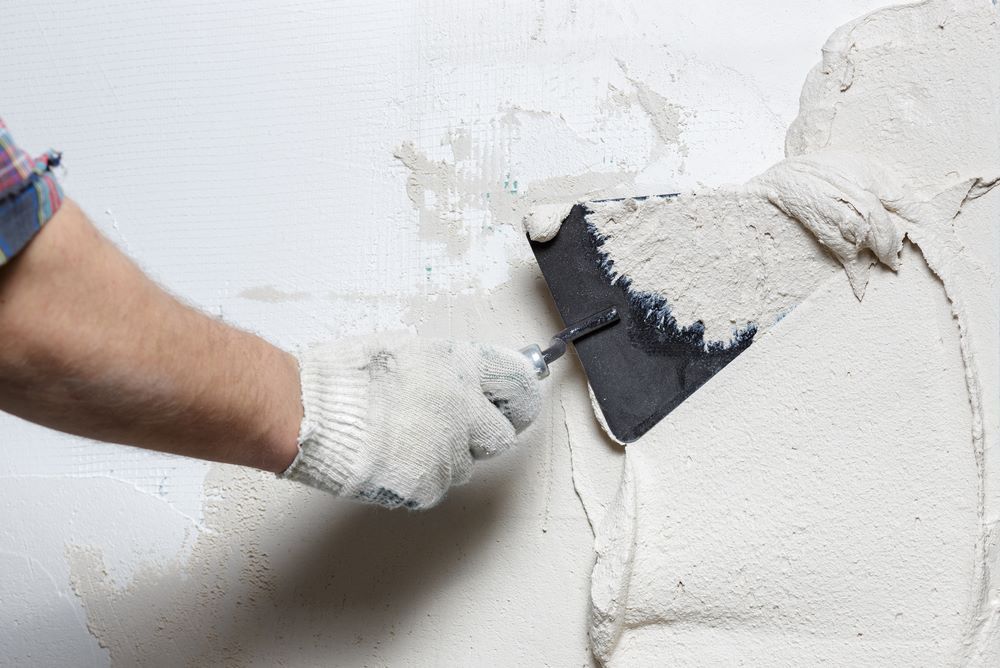 A Man is Plastering a Wall With a Margin Trowel — Clean Line Plastering in Diamond Beach, NSW