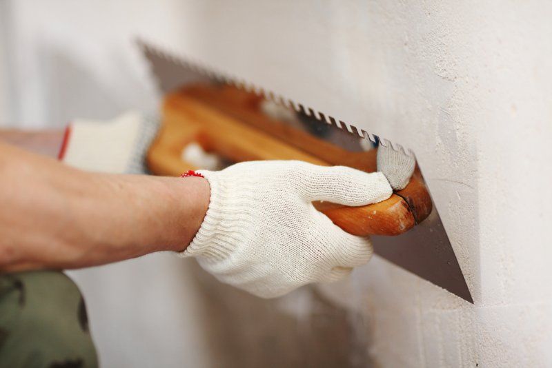 A Person is Plastering a Wall With a Trowel — Clean Line Plastering in Diamond Beach, NSW