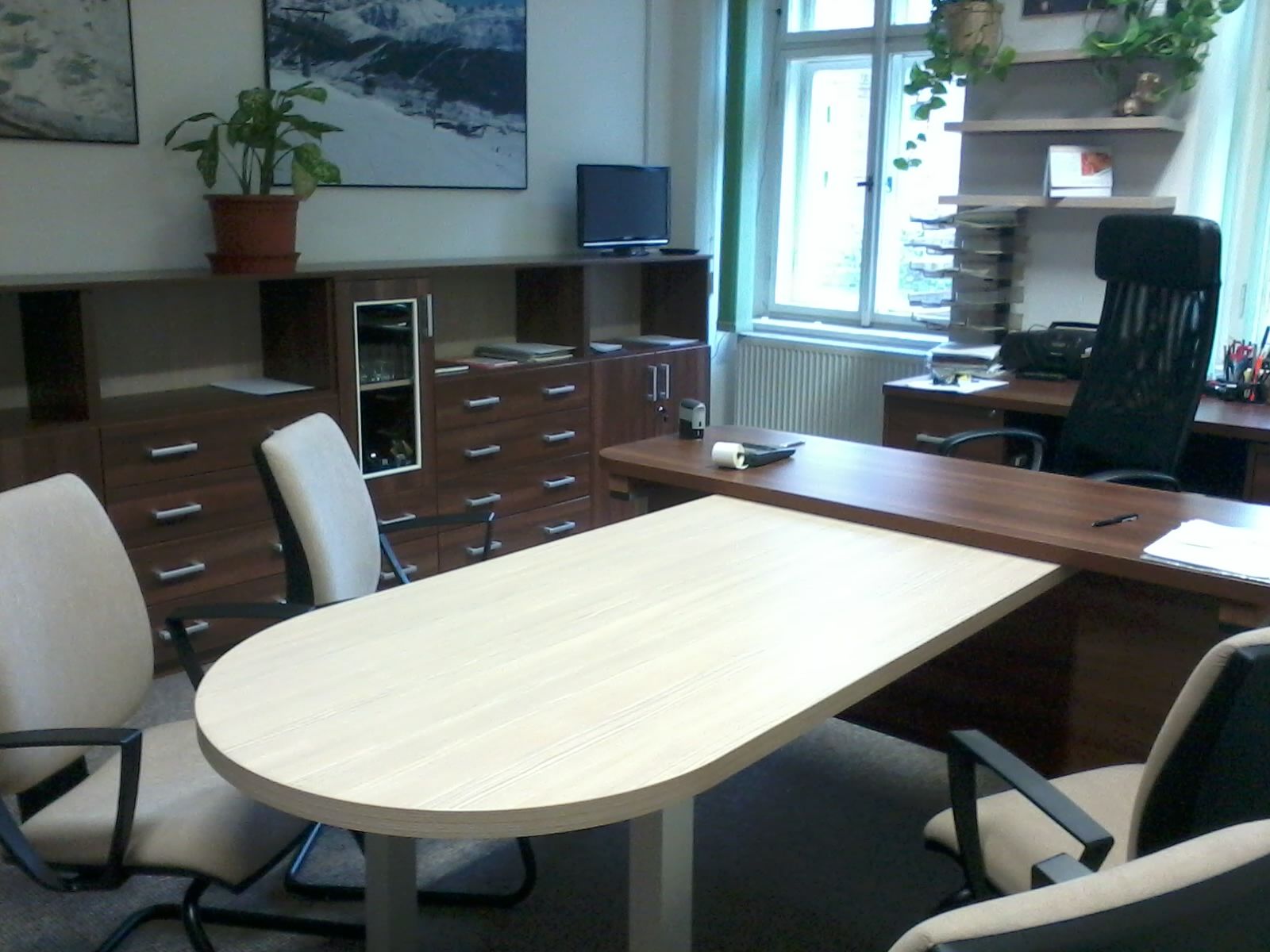 Un bureau avec un bureau en bois, des chaises et des armoires. Une fenêtre est visible en arrière-plan.