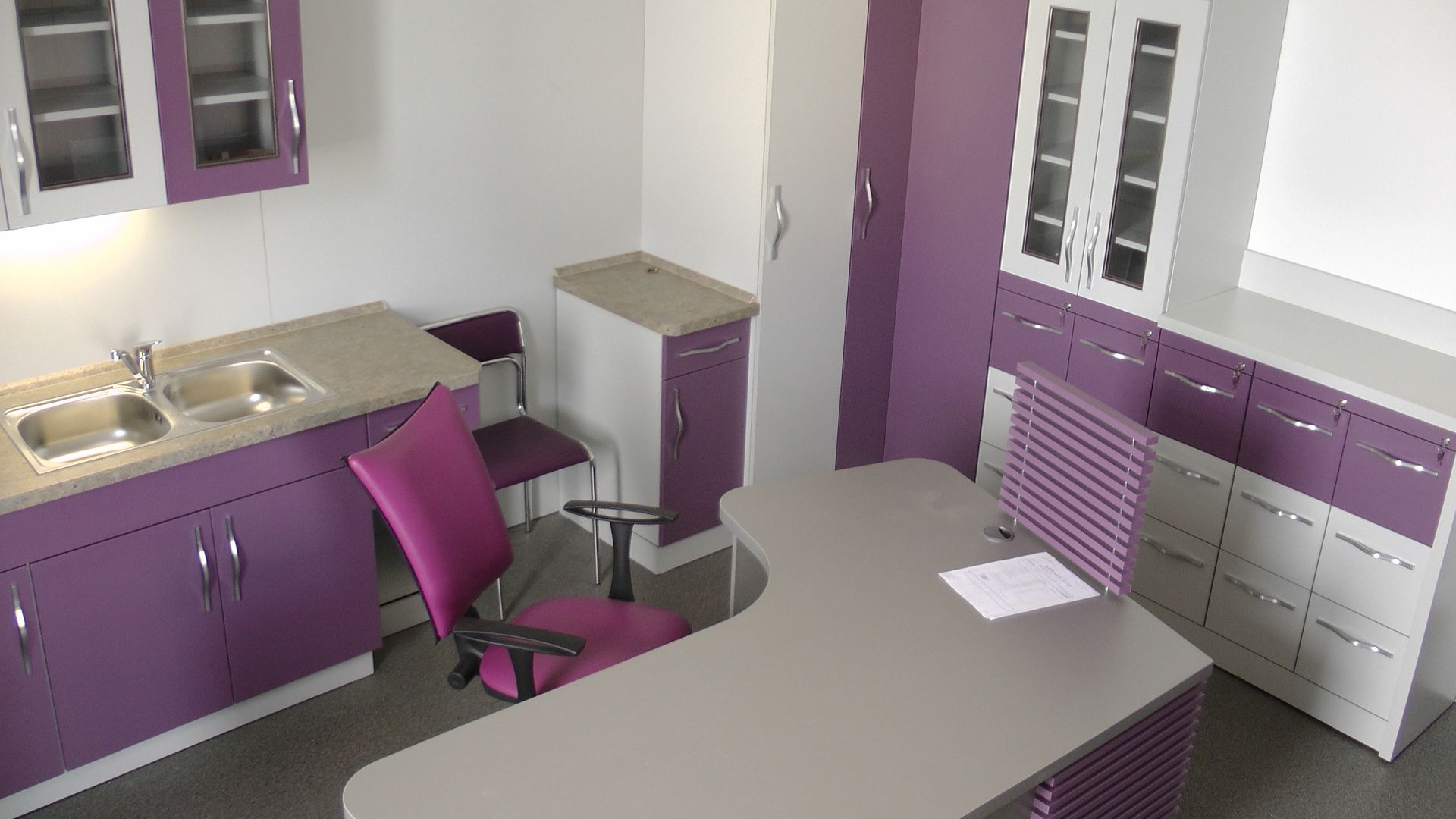 Bureau violet et blanc avec armoires, bureau, lavabo et chaise.