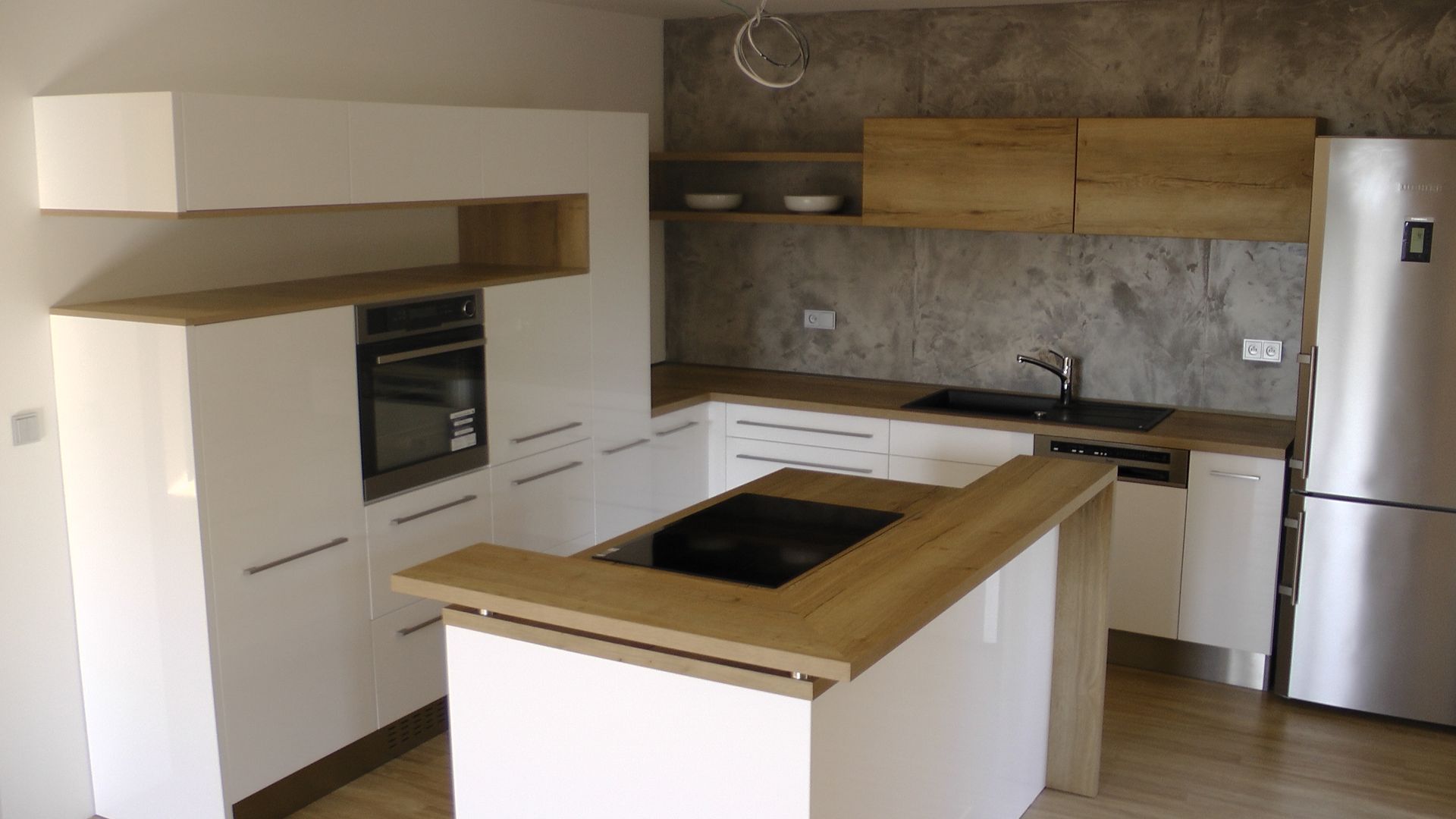 Cuisine moderne avec armoires blanches, touches de bois et électroménagers en acier inoxydable.