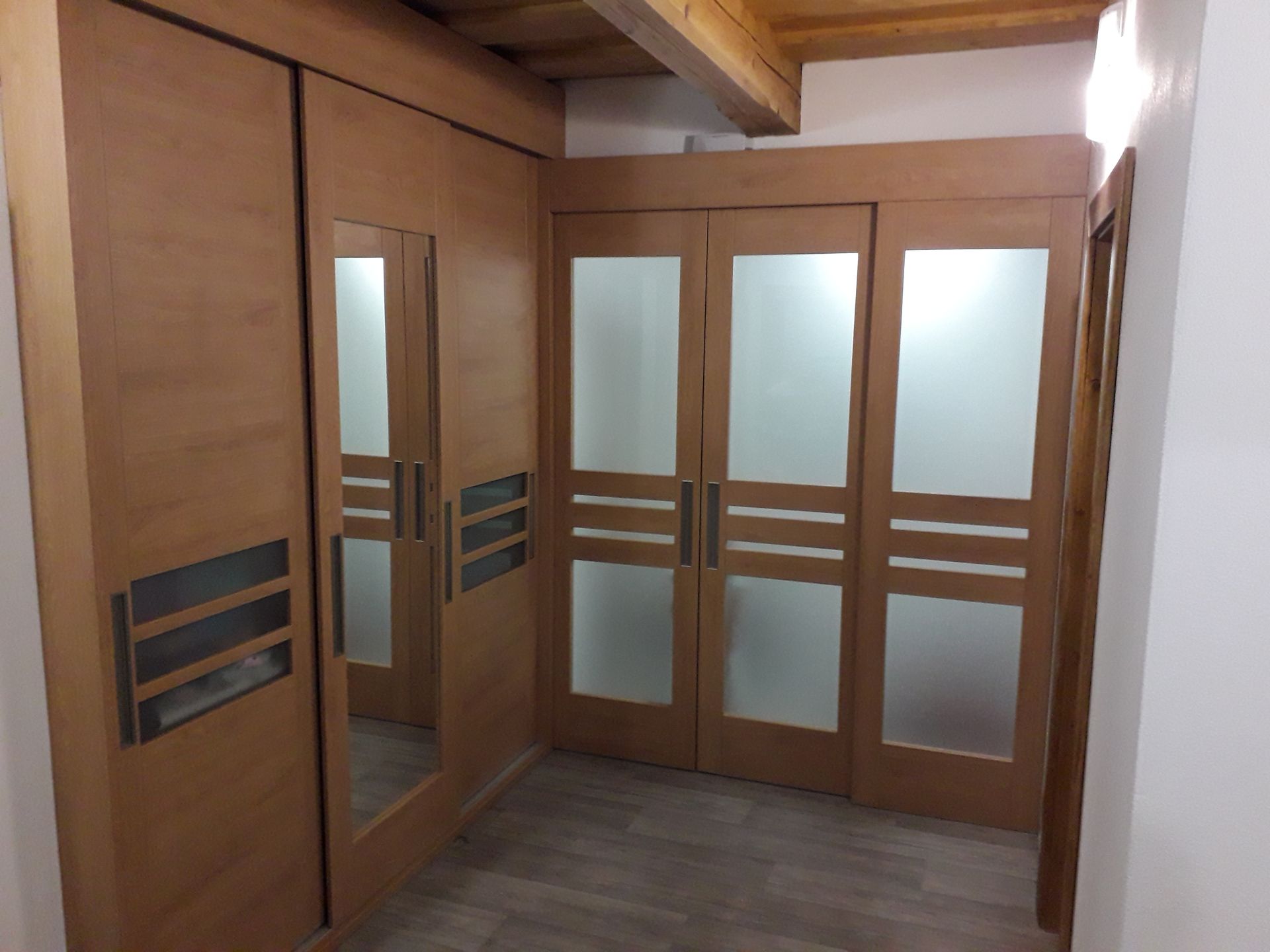 Placard en bois avec portes coulissantes en verre, miroir et poutres en bois.