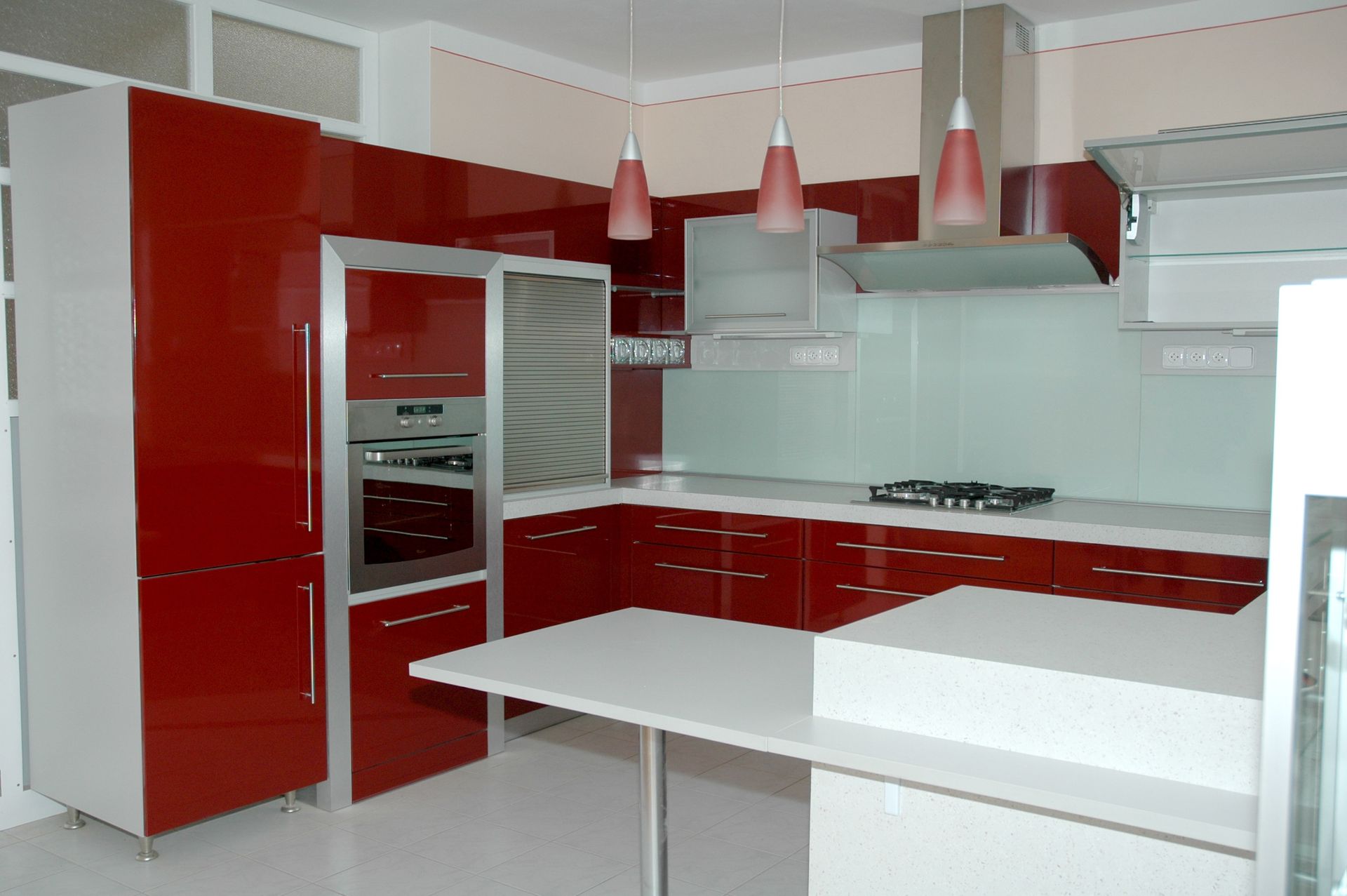 Cuisine moderne rouge et blanche avec armoires, électroménagers et îlot.