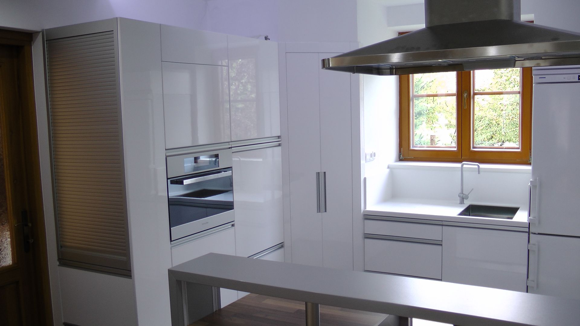 Cuisine blanche moderne avec appareils électroménagers en acier inoxydable et un bar pour le petit-déjeuner.