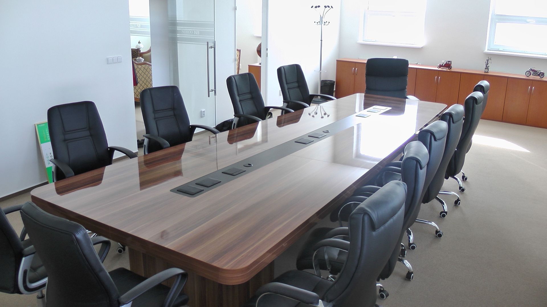 Salle de conférence avec grande table en bois et chaises en cuir noir.