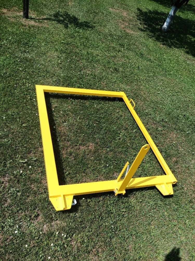 Cadre métallique jaune sur l'herbe, avec un support triangulaire et des roues.