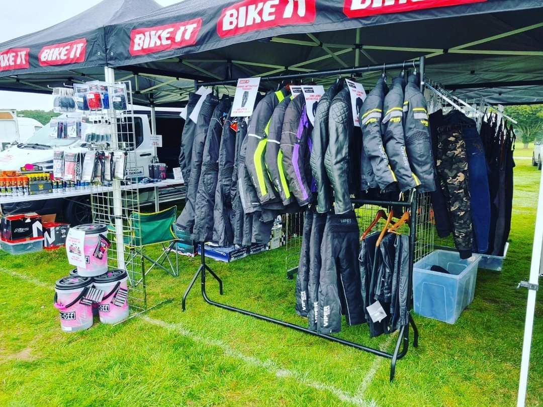 Bike It stall at an outdoor event, displaying motorcycle jackets and accessories under a canopy.