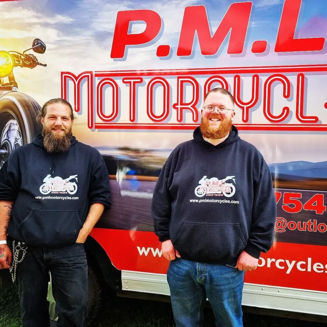 Two men stand in front of a van that says 