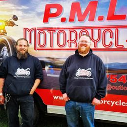 Two men stand in front of a van that says 