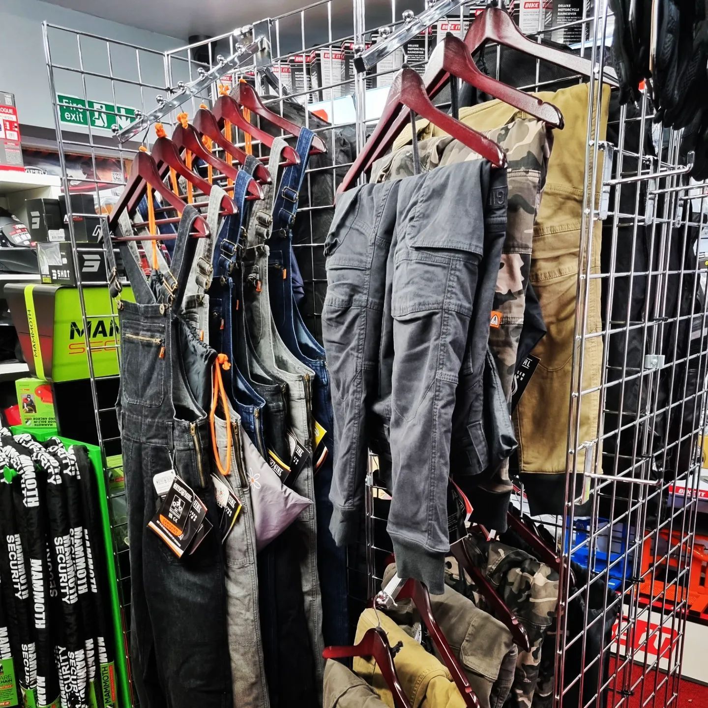 Clothing display with various pants and overalls hanging on racks in a store.