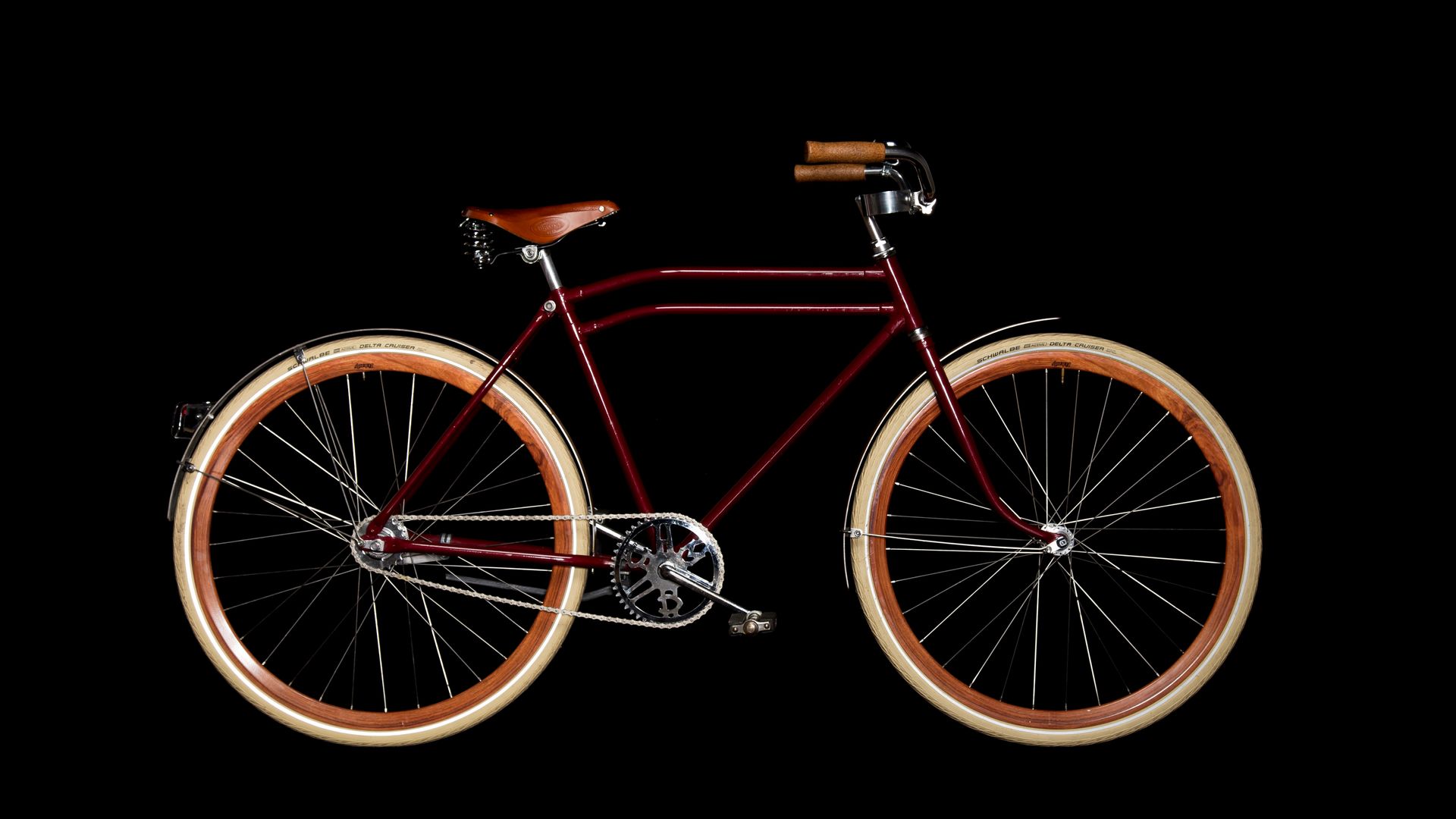 Red vintage bicycle with brown tires and leather seat.