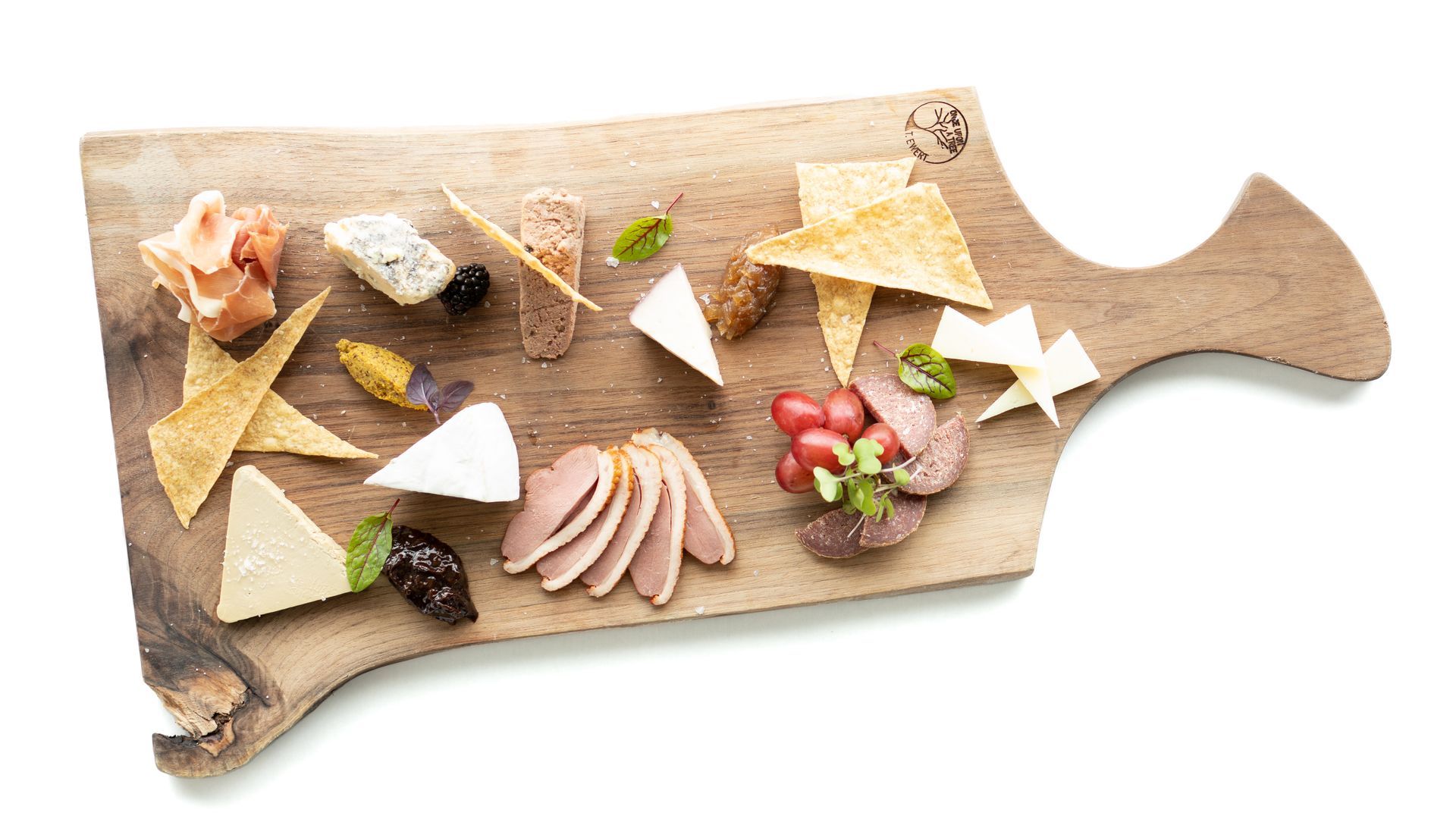 Charcuterie board with cheeses, meats, crackers, and grapes, on a wooden board.