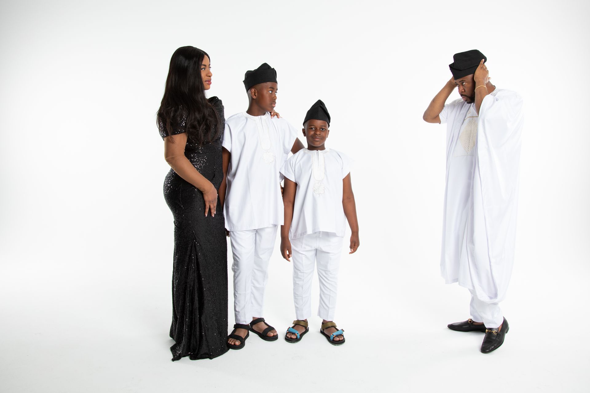 Family in white and black attire poses on a white background. Man holds his head, appearing stressed.
