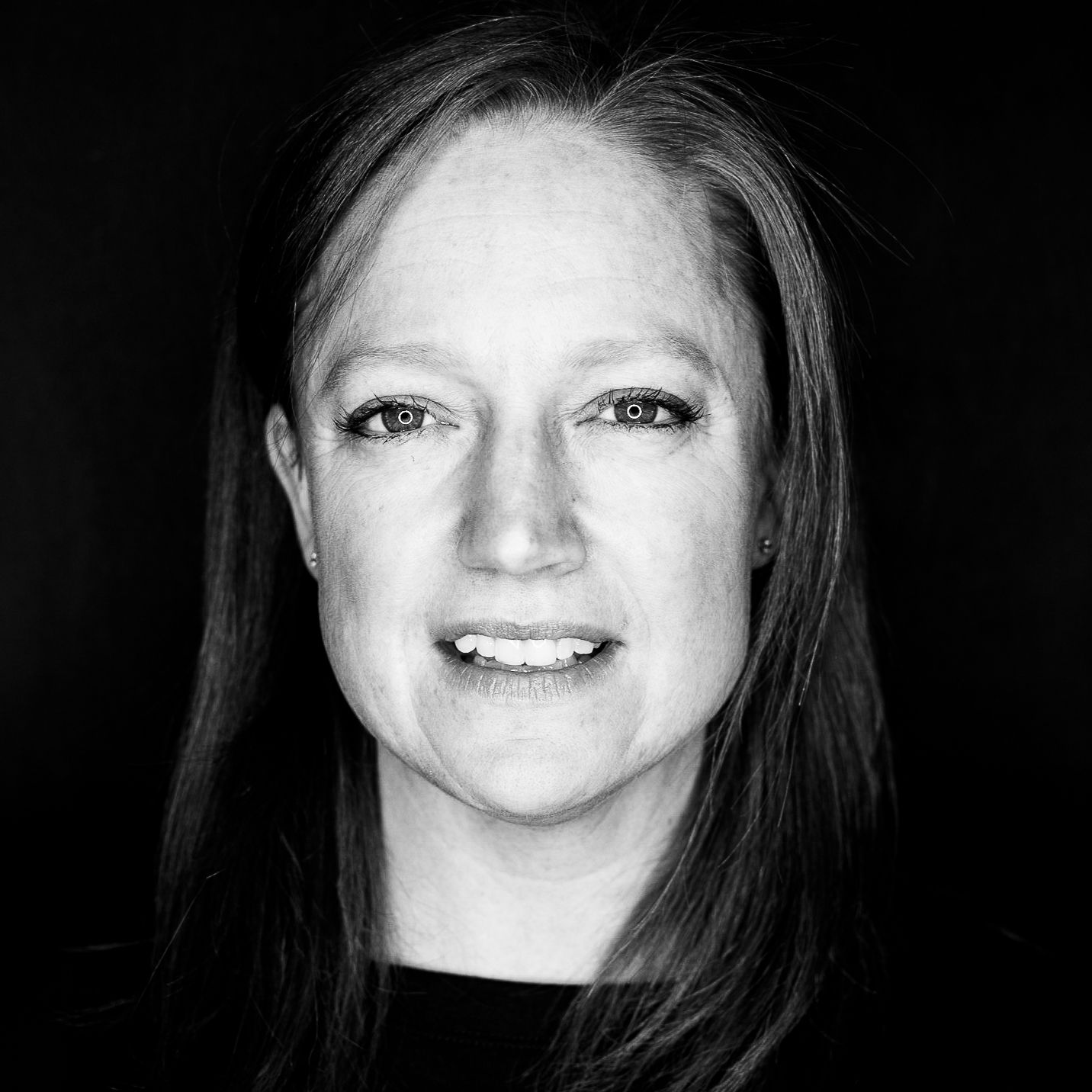 Woman with light skin, smiling, looking at the viewer; black and white portrait.