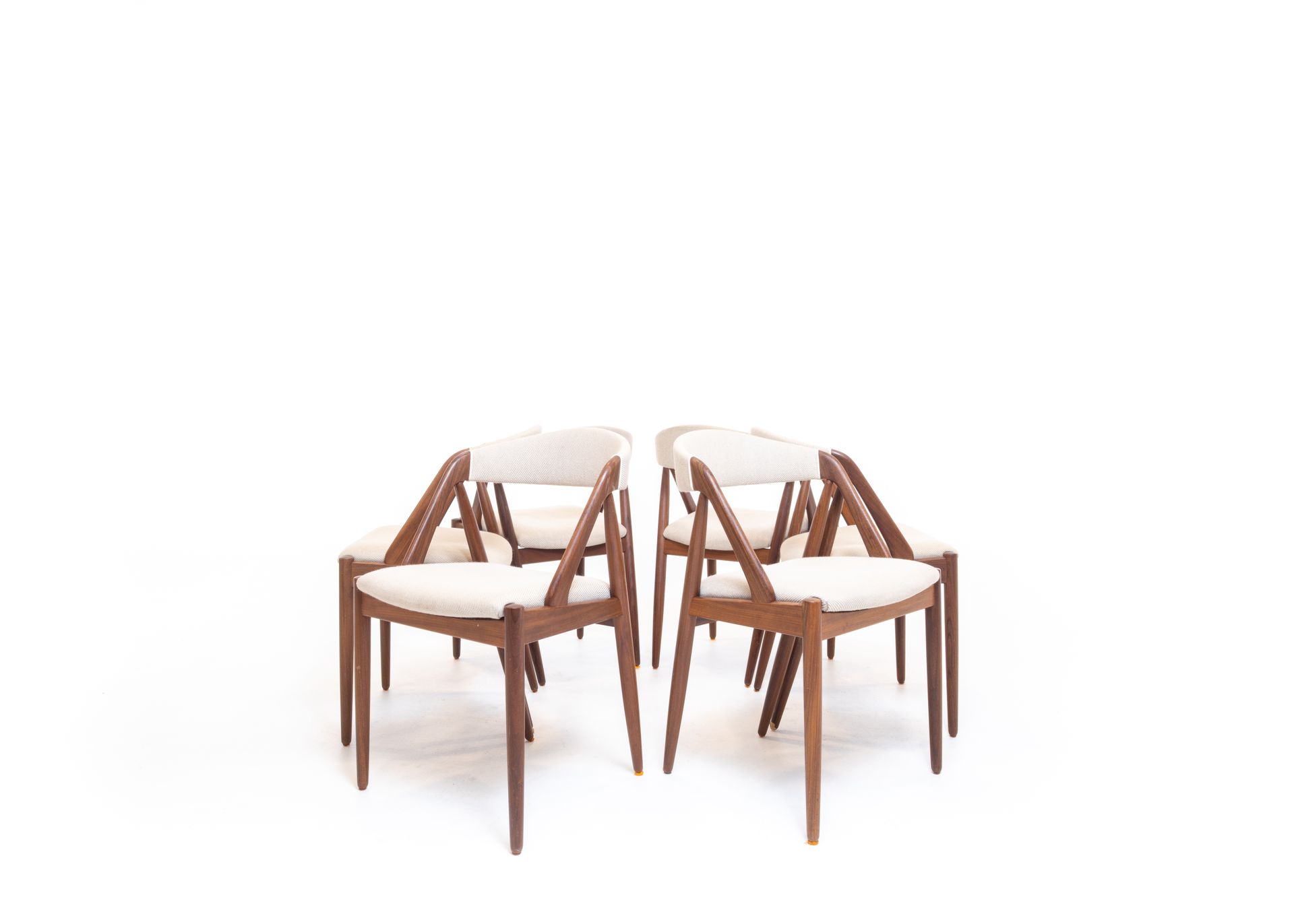 Six wooden chairs with cream-colored seats, arranged in a circle on a white background.