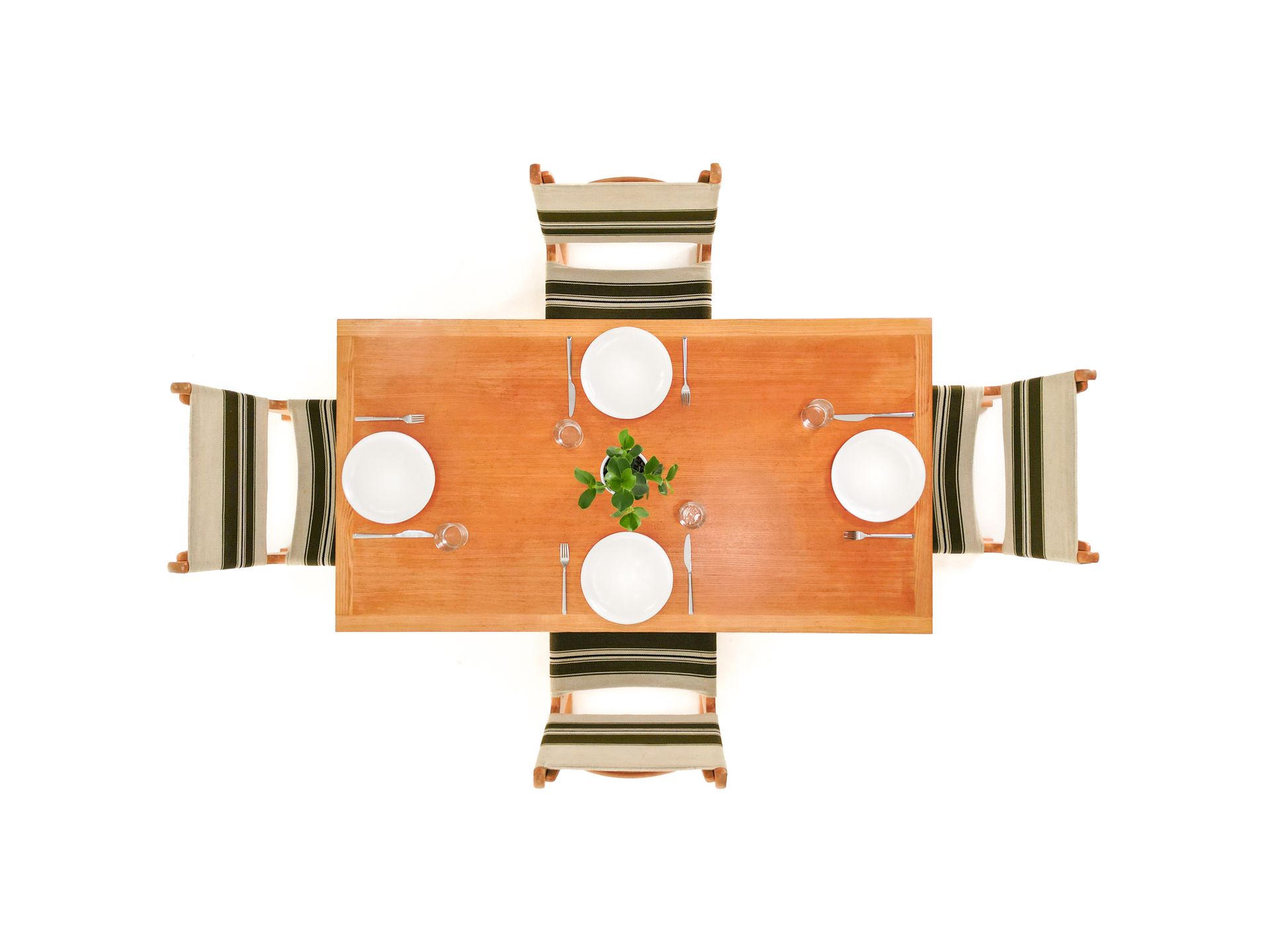 Overhead view of a wooden dining table set with four place settings, and chairs.