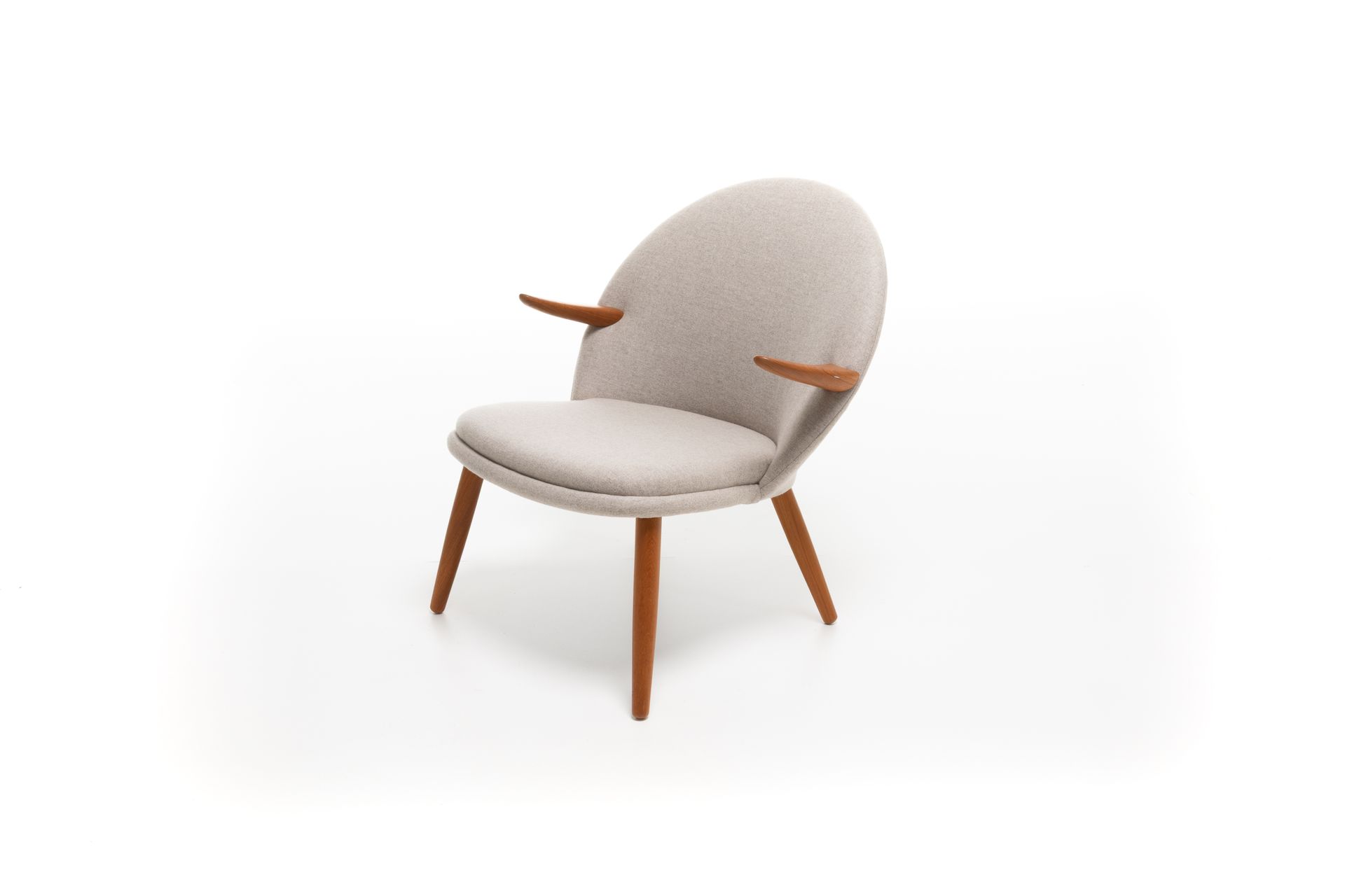 Light-colored upholstered armchair with wooden legs and armrests, against a white backdrop.