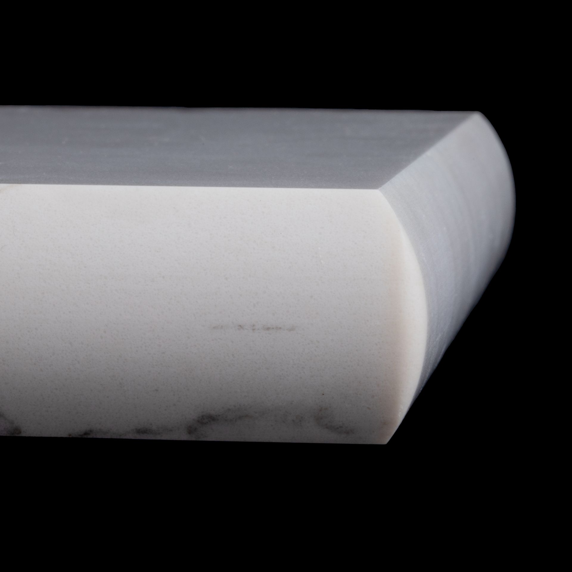 Close-up of a white countertop edge with a beveled, rounded corner.