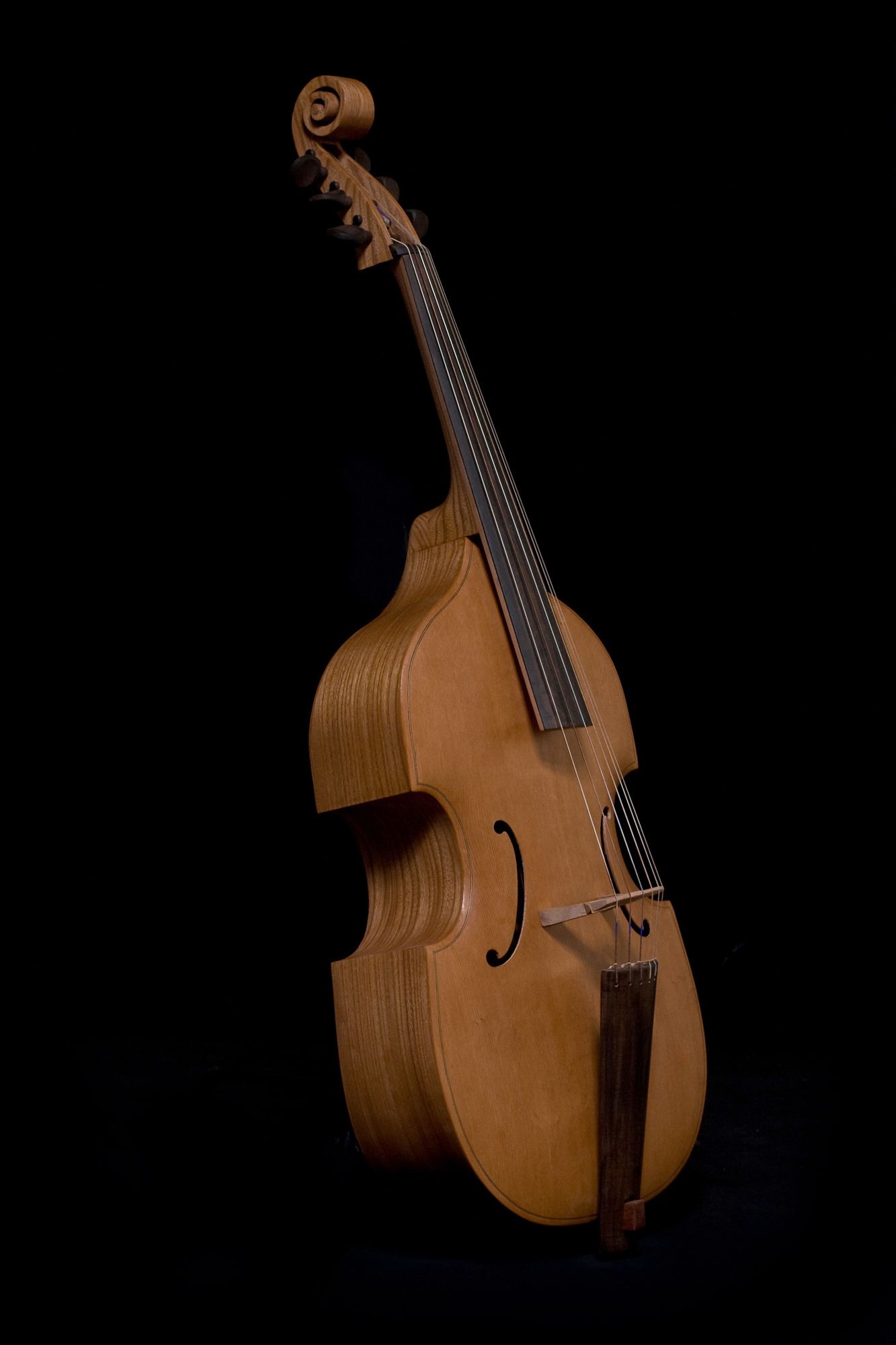 Wooden viola da gamba on a black background, showcasing its shape and detail.