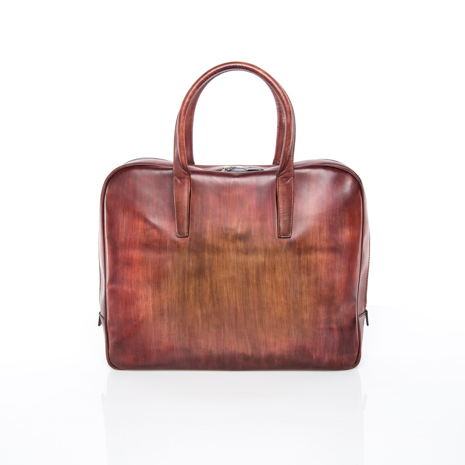 Brown leather briefcase with short handles, reflecting on a white surface.