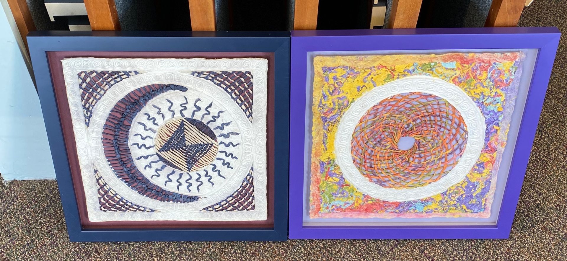 Two framed pictures are sitting on the floor next to each other.
