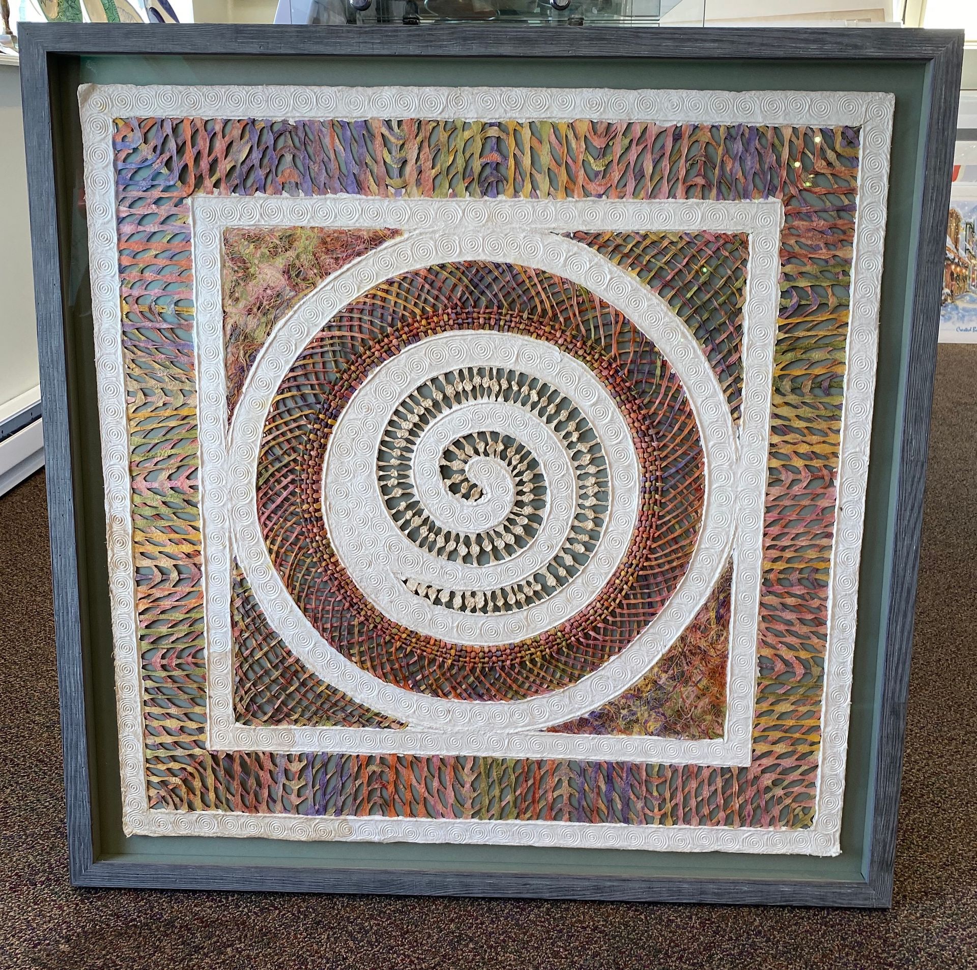 A quilt in a frame with a spiral in the center