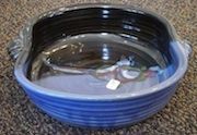 A blue and black bowl is sitting on a carpet.