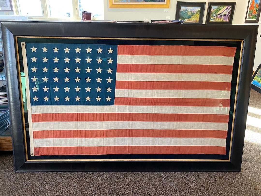 A framed american flag is sitting on the floor in a living room.