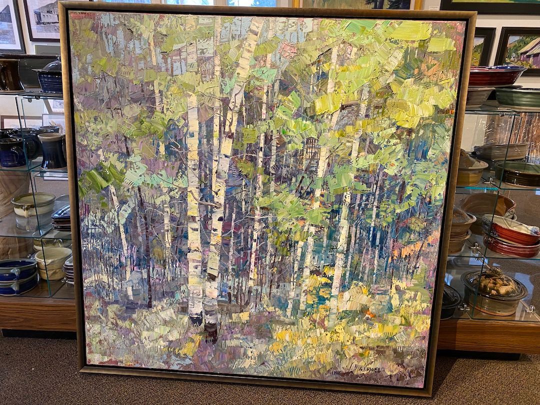 A painting of a forest with trees and leaves is sitting on a table.