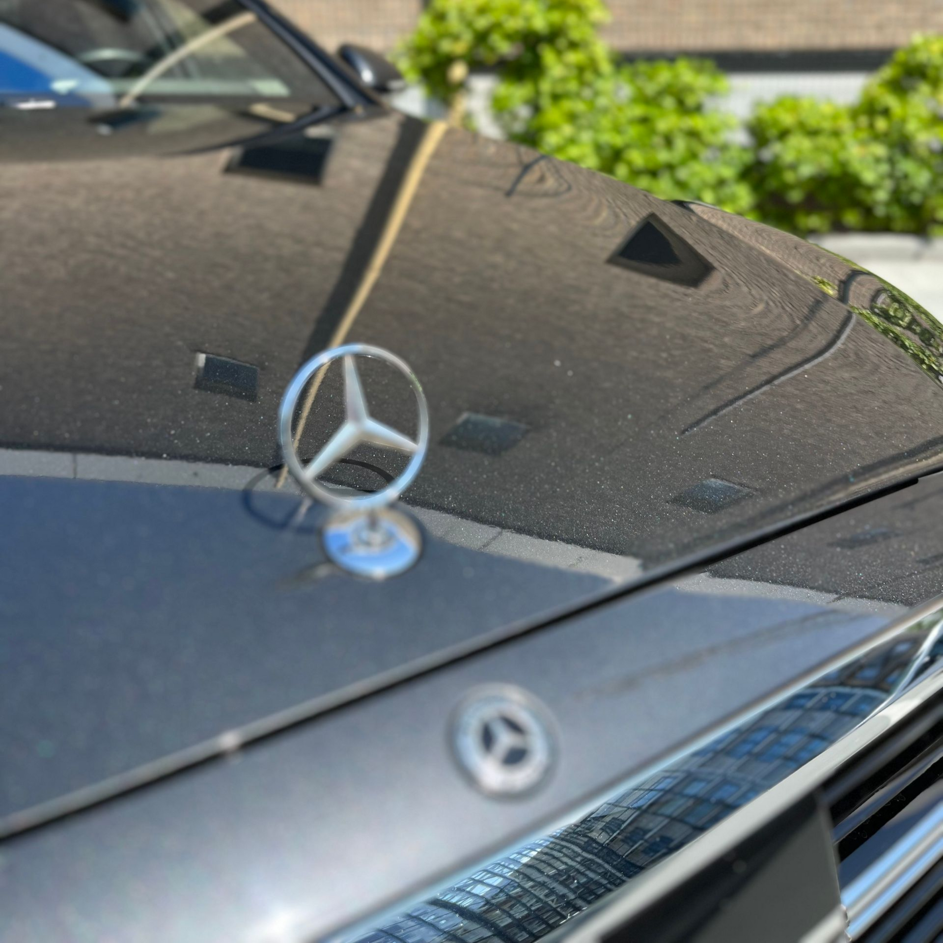 Close-up van de motorkap van een zwarte Mercedes-Benz met het iconische embleem.