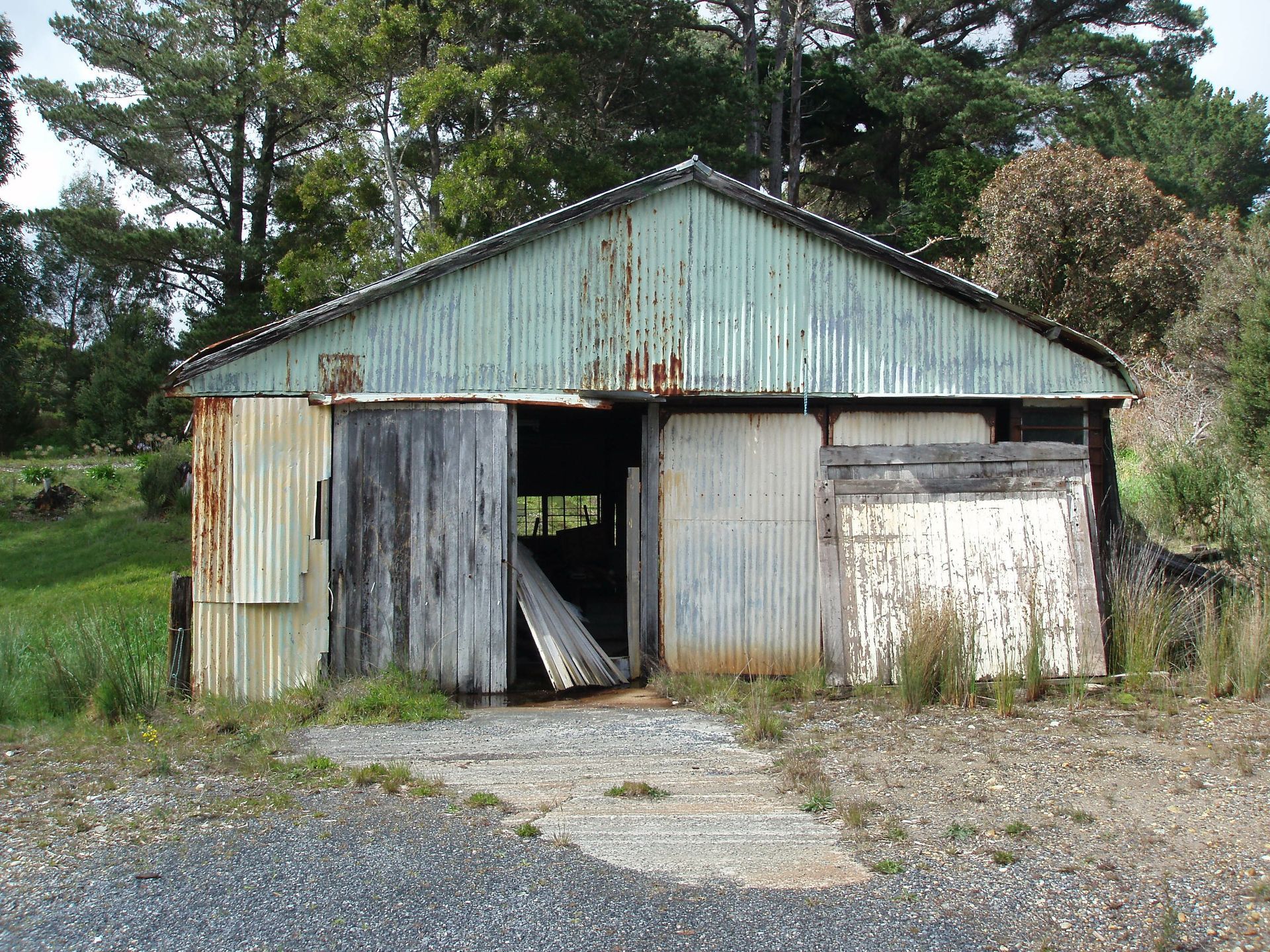 A rusty shed with a green roof and white doors