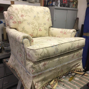 Floral upholstered armchair with matching ottoman in a cluttered workshop setting