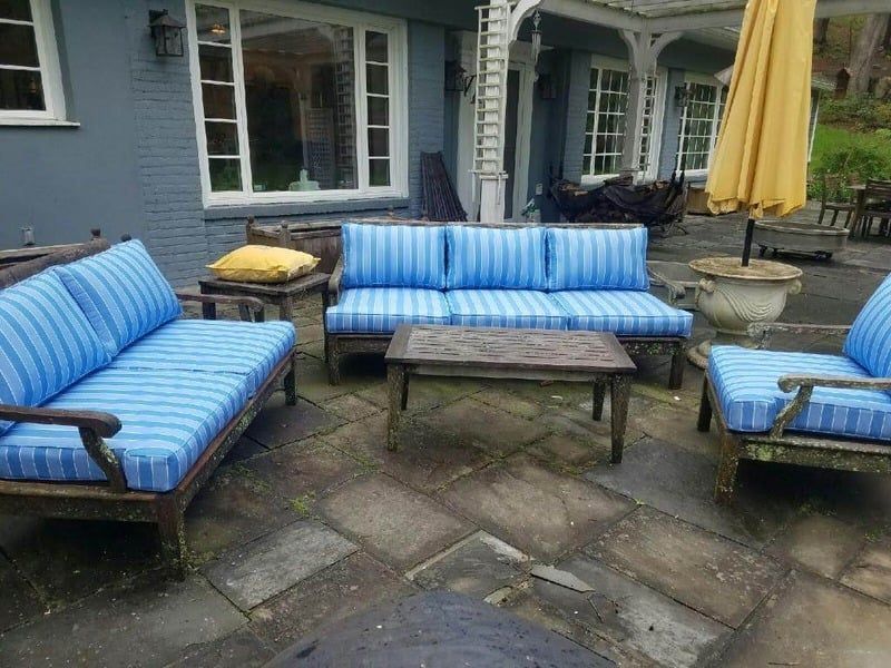 Blue striped outdoor patio furniture around a wooden coffee table on a stone terrace.