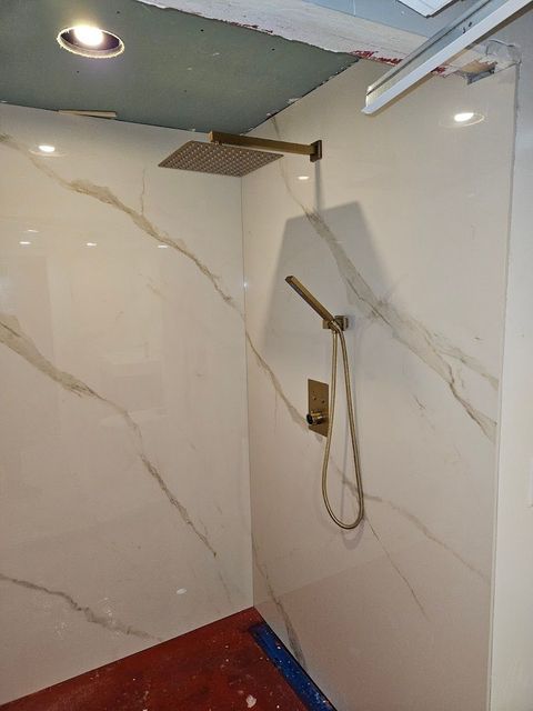 A bathroom with a shower head on the wall and a red floor.