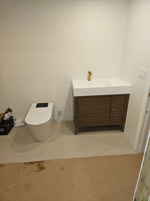 A bathroom with a toilet , sink and vanity.