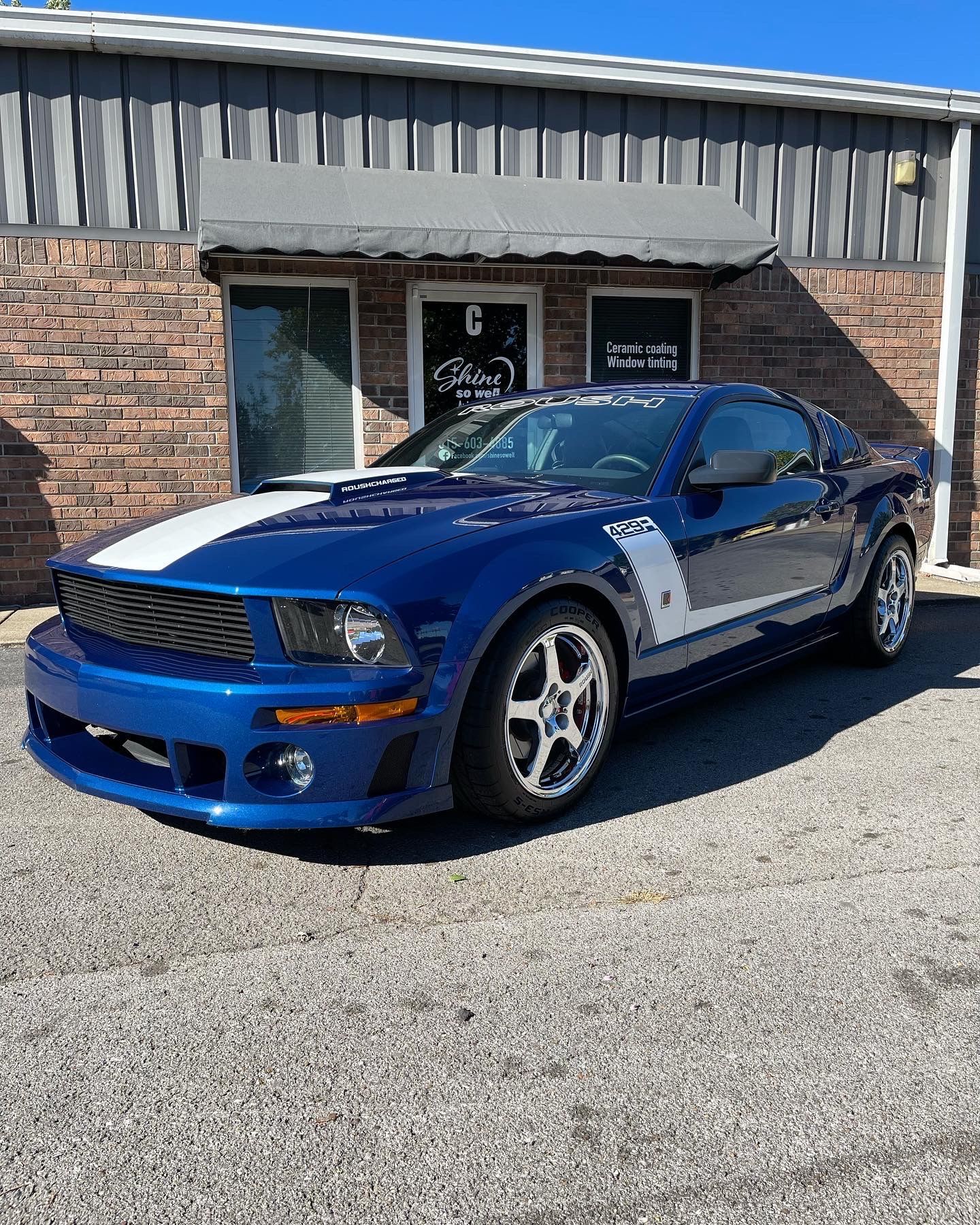 Blue and white striped Ford Mustang parked in front of a brick building.