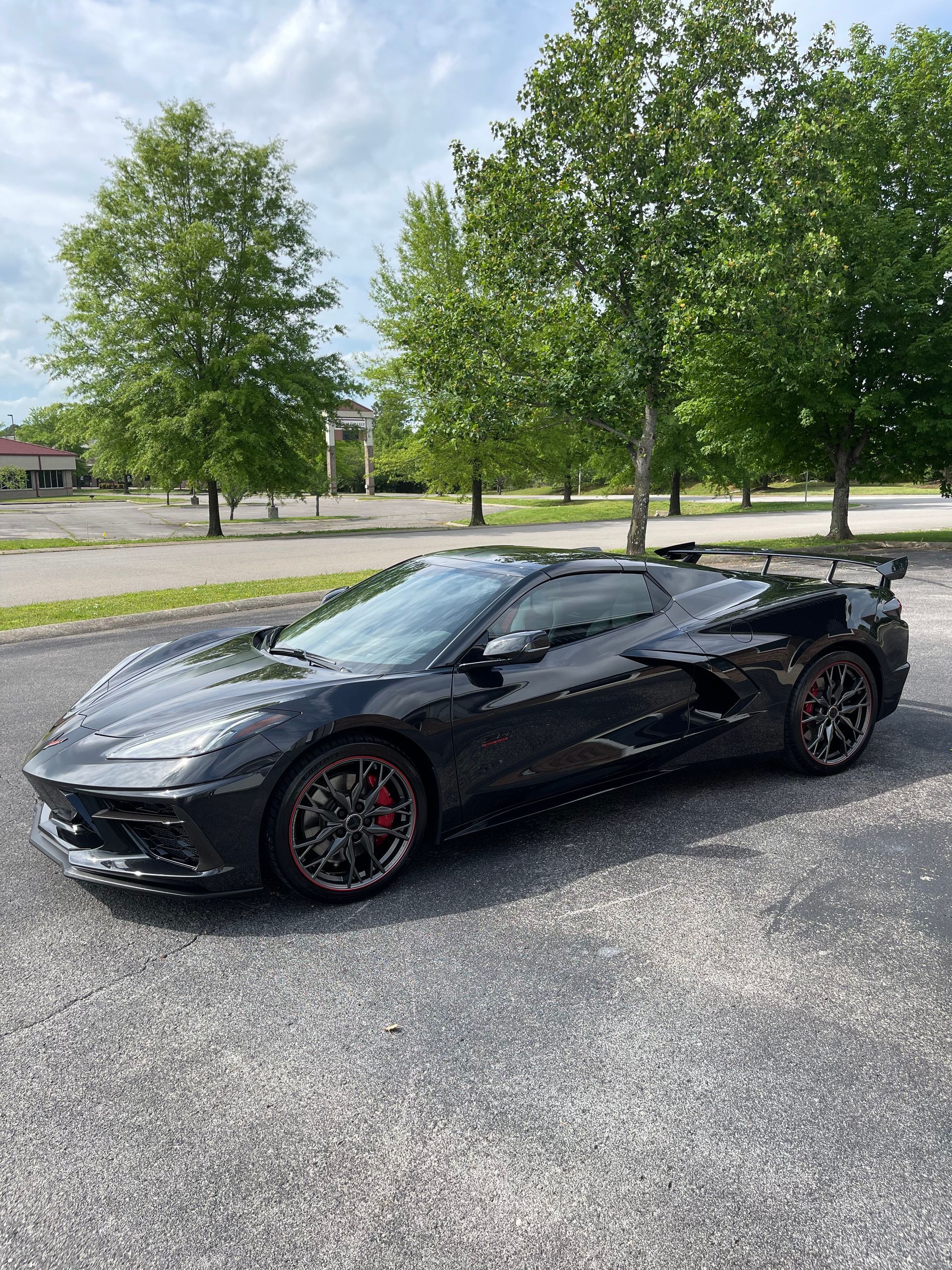 Dark gray Corvette sports car parked on asphalt, trees in background.